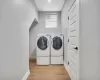 Laundry area with washer and dryer and light hardwood / wood-style floors