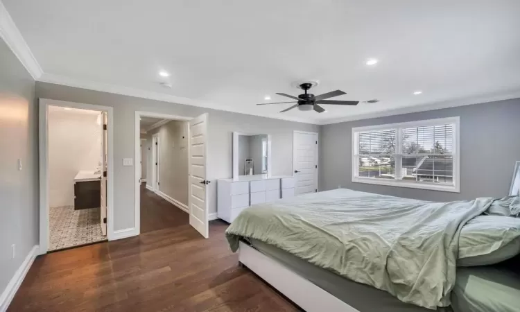 Bedroom with ceiling fan, dark hardwood / wood-style floors, crown molding, and ensuite bath