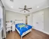 Bedroom featuring ceiling fan, ornamental molding, dark wood-type flooring, and a closet