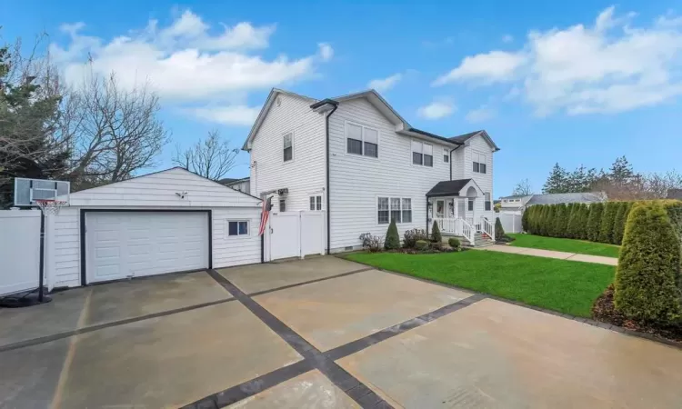 View of front of property featuring an outdoor structure, central AC, a front yard, and a garage