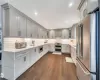 Kitchen featuring light stone countertops, dark hardwood / wood-style flooring, gray cabinetry, custom exhaust hood, and stainless steel appliances