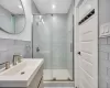 Bathroom featuring vanity, an enclosed shower, decorative backsplash, and tile walls