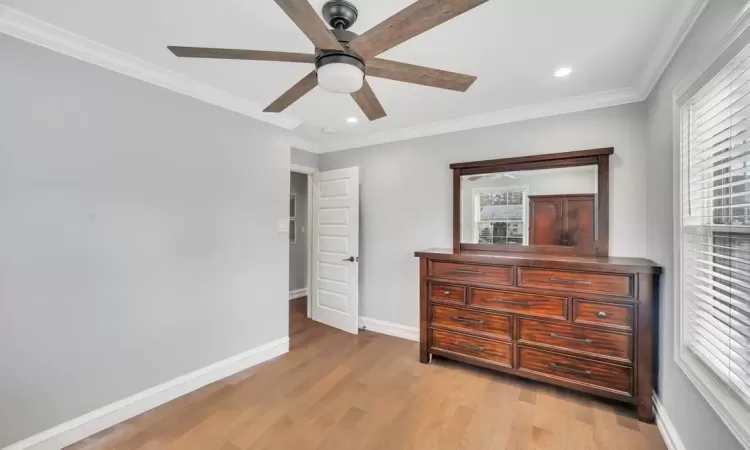 Bedroom featuring ceiling fan, light wood-type flooring, and ornamental molding