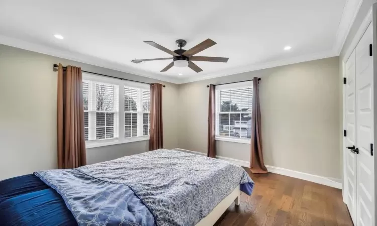 Bedroom with ceiling fan, crown molding, dark wood-type flooring, and multiple windows