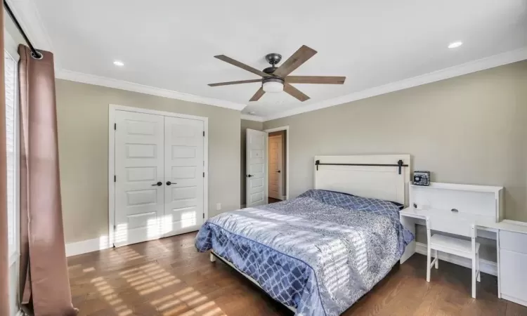 Bedroom featuring a closet, dark hardwood / wood-style floors, ceiling fan, and ornamental molding