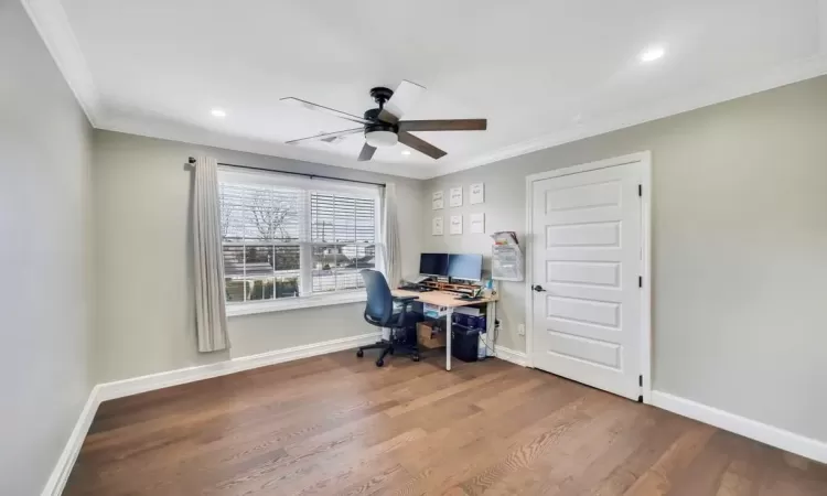 Office area with ceiling fan, dark wood-type flooring, and ornamental molding