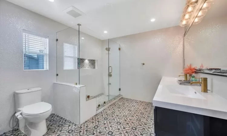 Bathroom featuring tile patterned floors, vanity, an enclosed shower, and toilet