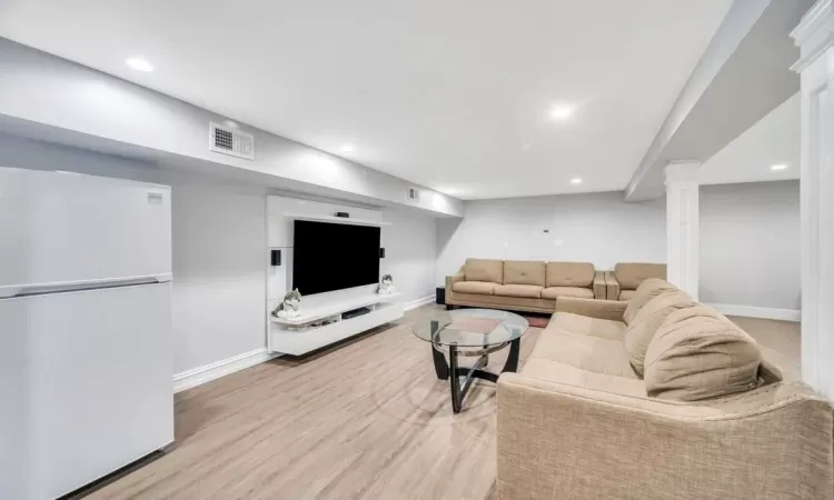 Living room with decorative columns and light hardwood / wood-style floors