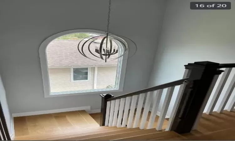 Staircase with a chandelier and hardwood / wood-style floors