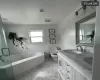 Bathroom with vanity, a relaxing tiled tub, and toilet