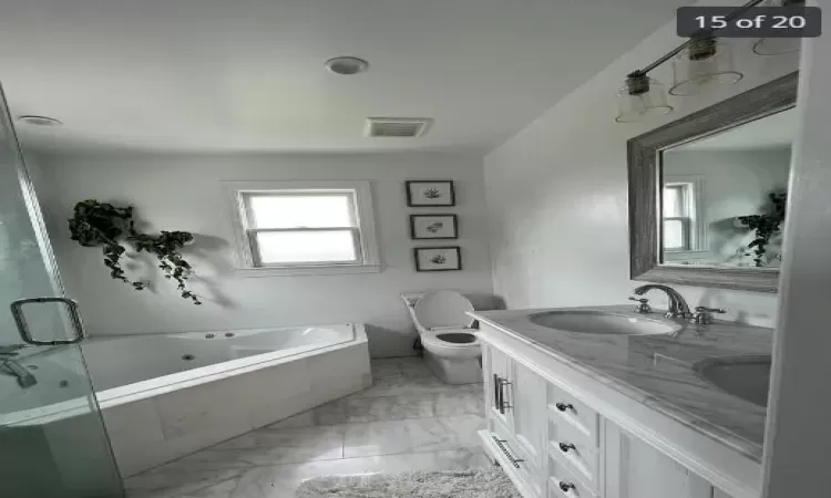 Bathroom with vanity, a relaxing tiled tub, and toilet