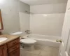 Full bathroom with vanity, tiled shower / bath combo, and toilet