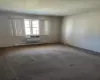 Carpeted spare room featuring baseboard heating and an AC wall unit