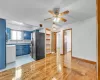 Kitchen featuring ceiling fan, black fridge, blue cabinets, backsplash, and light hardwood / wood-style floors