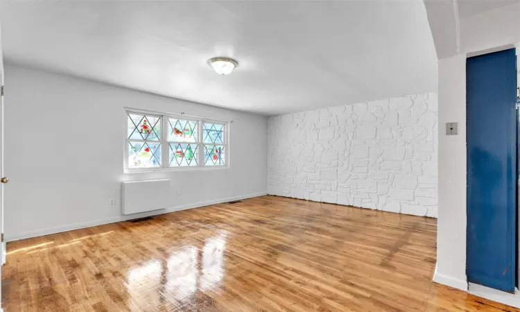 Empty room featuring elevator and wood-type flooring