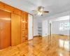 Additional living space with built in shelves, ceiling fan, radiator heating unit, and light hardwood / wood-style flooring