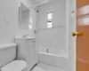 Full bathroom featuring tile walls, vanity, tiled shower / bath combo, and toilet