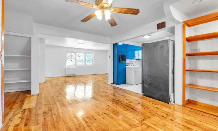 Unfurnished living room featuring washer / dryer, light wood-type flooring, and ceiling fan