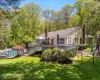 Rear view of property featuring a playground, a deck, and a lawn