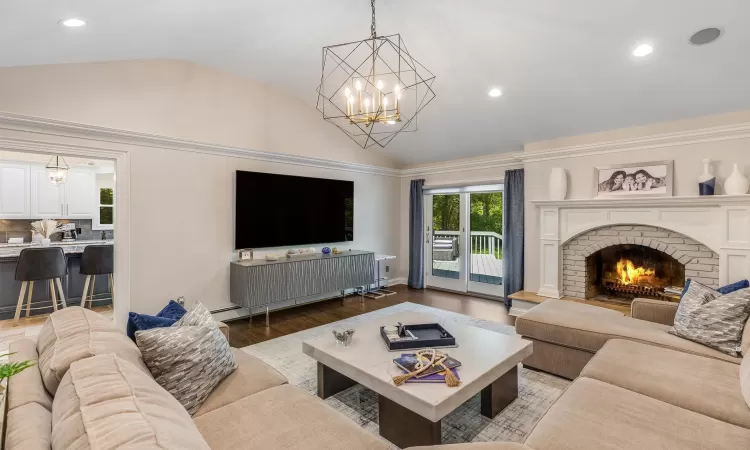 Living room with hardwood / wood-style floors, a fireplace, a chandelier, and vaulted ceiling