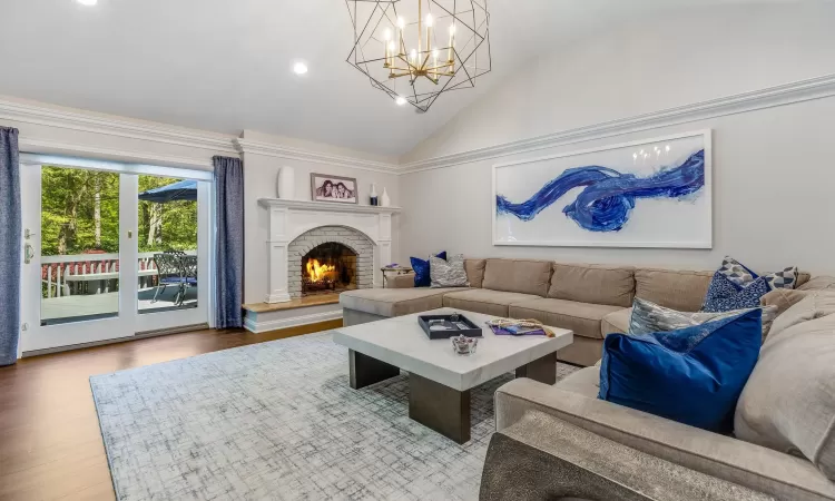 Living room featuring hardwood / wood-style flooring, lofted ceiling, a fireplace, and an inviting chandelier