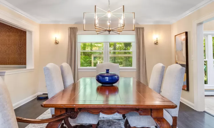 Dining space featuring a notable chandelier, dark hardwood / wood-style flooring, ornamental molding, and baseboard heating