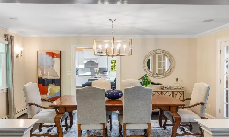 Dining space with crown molding, baseboard heating, and a notable chandelier