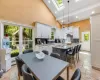 Kitchen featuring a center island, a kitchen breakfast bar, light stone counters, high vaulted ceiling, and pendant lighting