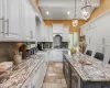 Kitchen with white cabinets, a kitchen island, light stone countertops, and hanging light fixtures