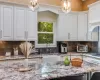 Kitchen featuring light stone countertops, sink, pendant lighting, stovetop, and white cabinetry