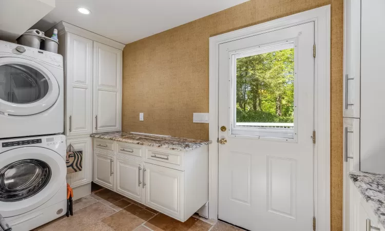 Laundry room with stacked washer / dryer and cabinets