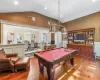 Game room with a chandelier, wood-type flooring, lofted ceiling, and pool table