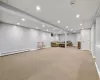 Basement featuring baseboard heating and light carpet