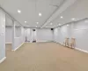 Basement featuring light carpet, a baseboard radiator, and white refrigerator