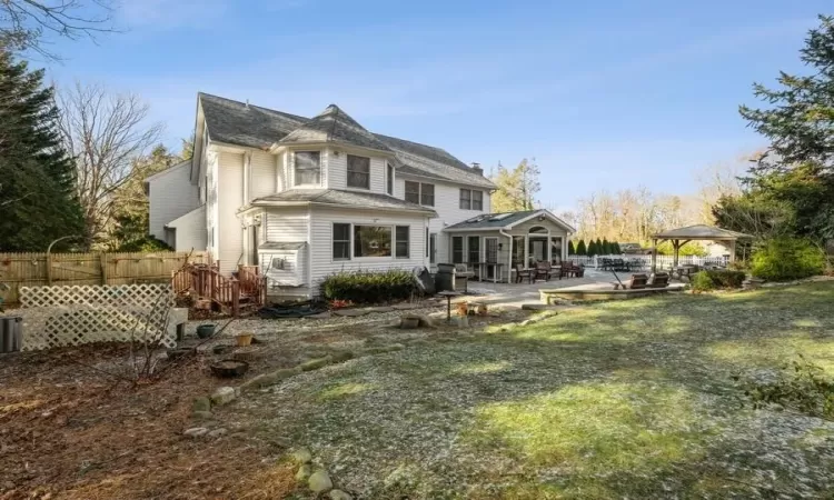 Rear view of property with a gazebo, a patio area, and a lawn