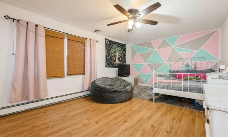 Bedroom with hardwood / wood-style flooring, ceiling fan.