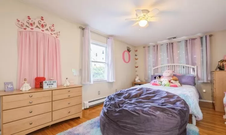 Bedroom with ceiling fan, light wood-type flooring.