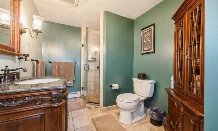 Bathroom with vanity,  a shower with door, tile patterned flooring, and toilet