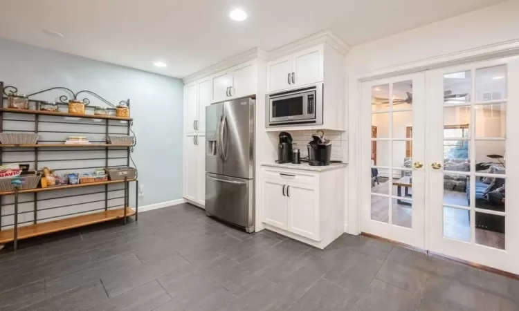 Kitchen featuring tasteful backsplash, french doors, white cabinets, and appliances with stainless steel finishes