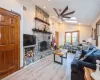 Den with a fireplace, light wood-type flooring, ceiling fan, and vaulted ceiling with skylight