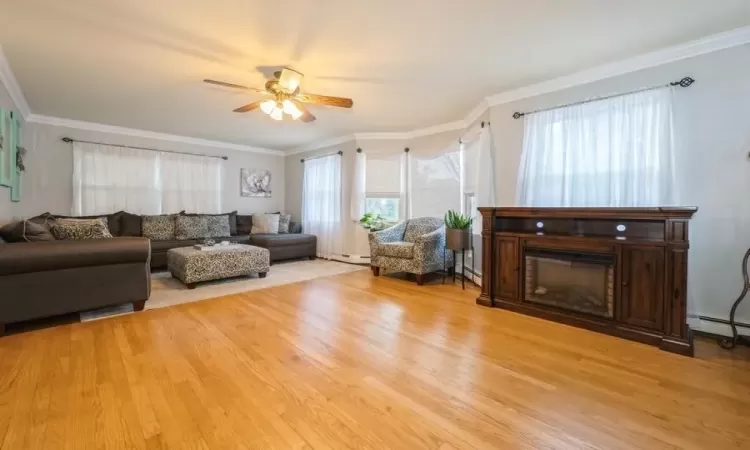 Living room with ceiling fan, light hardwood / wood-style floors, and ornamental molding