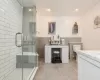 Bathroom featuring vanity, tile walls, and walk in shower