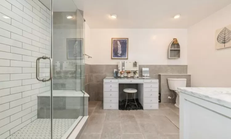 Bathroom featuring vanity, tile walls, and walk in shower