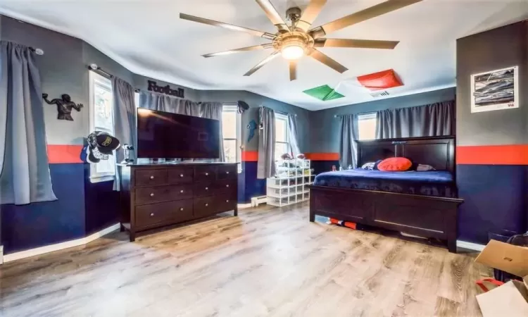 Bedroom featuring ceiling fan, light hardwood / wood-style floors and multiple windows