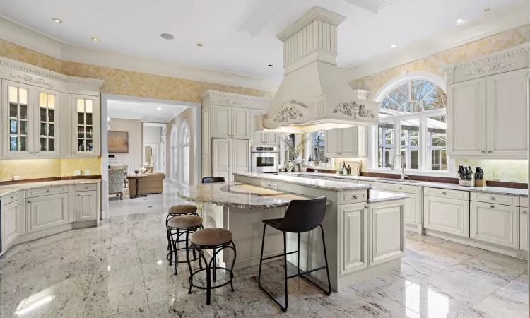 Kitchen featuring light stone countertops, white cabinetry, sink, a kitchen bar, and a kitchen island