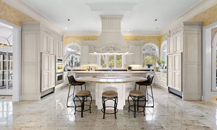 Kitchen featuring sink, stainless steel double oven, a kitchen breakfast bar, crown molding, and a kitchen island