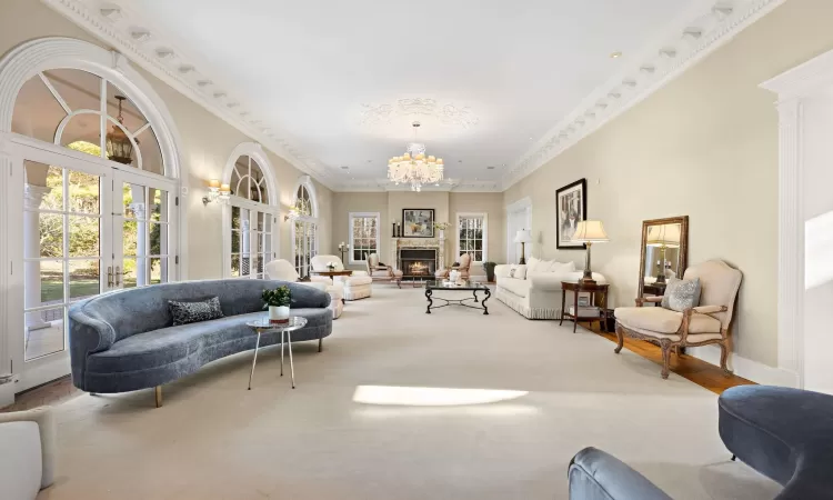 Living room featuring carpet, a notable chandelier, crown molding, and french doors