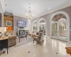 Tiled living room featuring a healthy amount of sunlight, french doors, and a chandelier