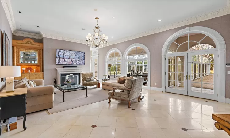 Tiled living room featuring a healthy amount of sunlight, french doors, and a chandelier