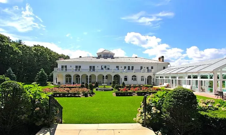 Back of house with a yard and a balcony